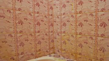 Een badkamer met toilet, betegelde wanden en een vloer met een patroon.