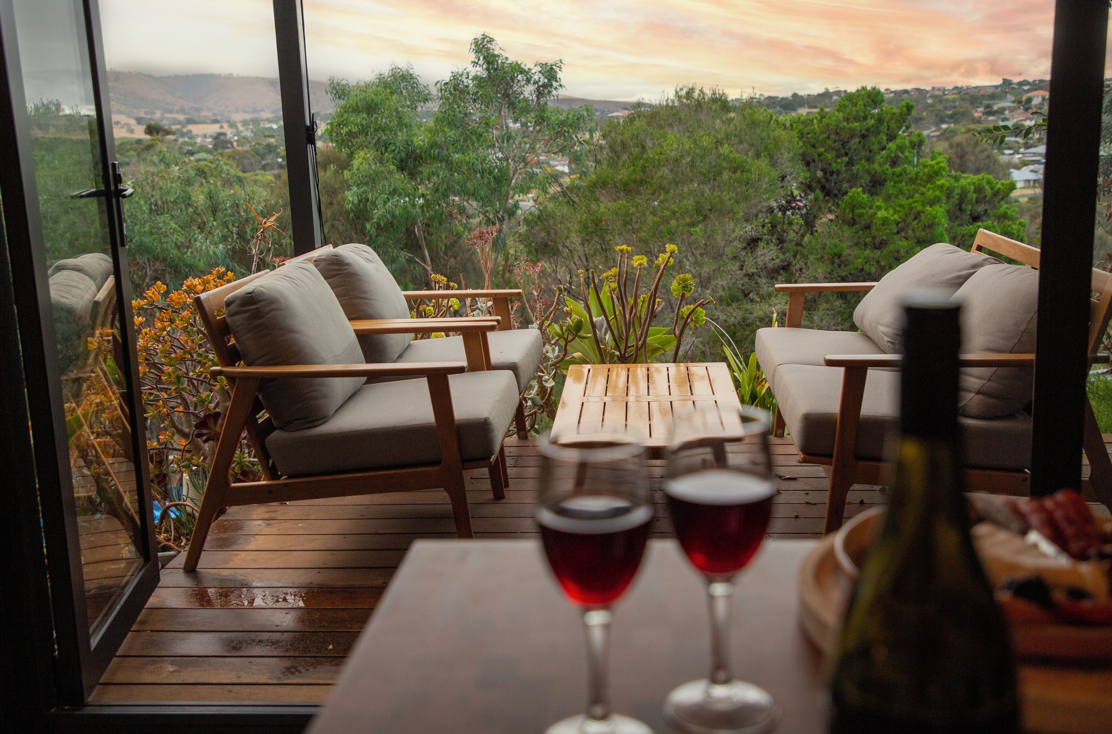 A wooden deck with two sofas and a table, overlooking a scenic landscape.