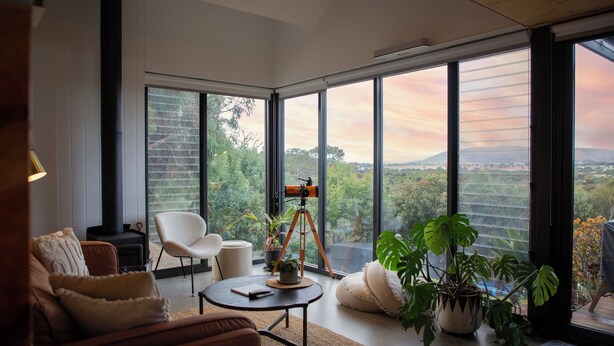 A modern living room with a large window, a telescope, and comfortable seating. - Wren House Victor Harbor (Victor Harbor)