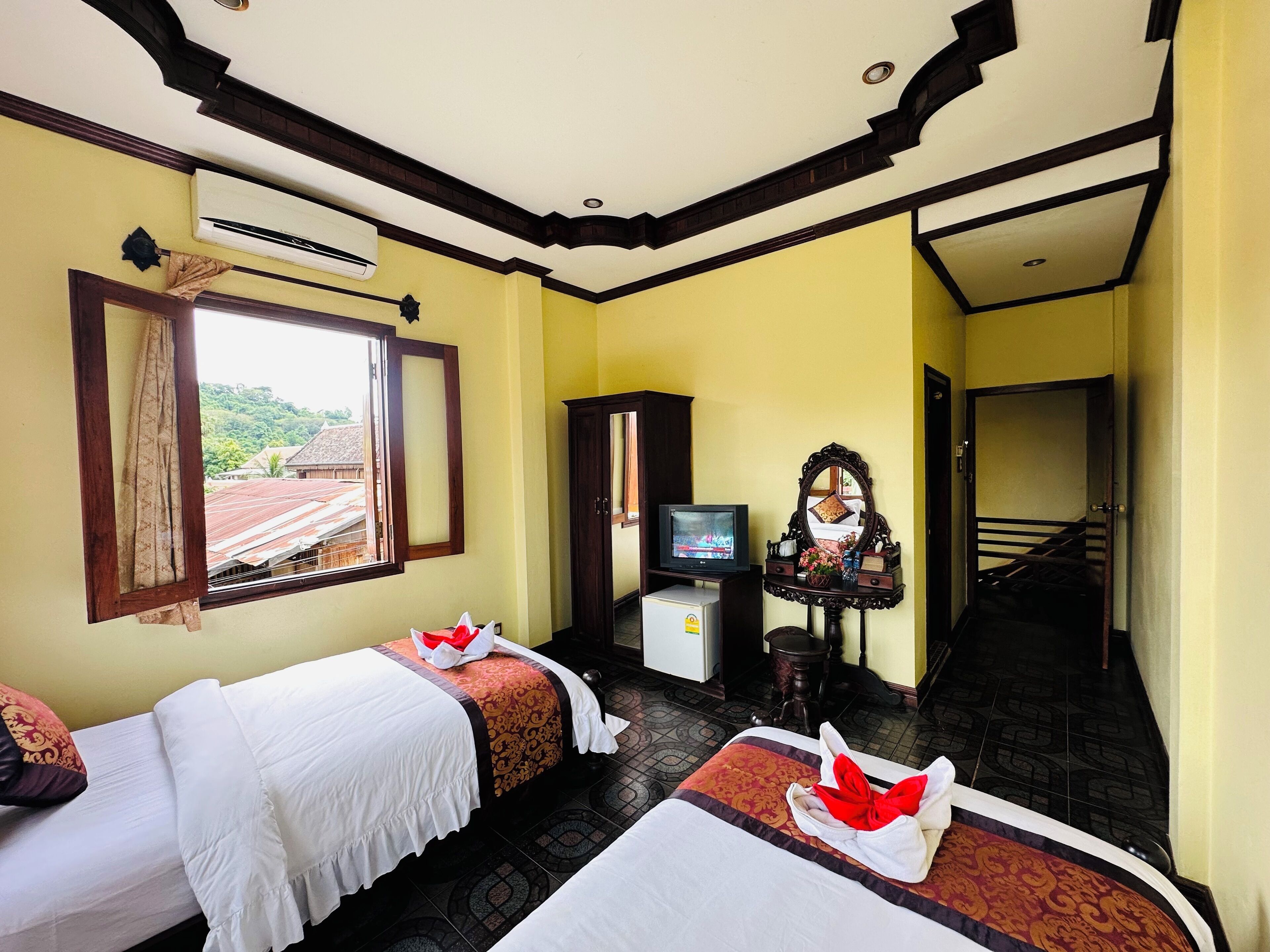 A hotel room with two beds, a television, a mirror, and a staircase.