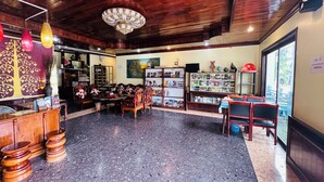 Een ruime lobby met een houten plafond, een receptiebalie, een zithoek en een boekenkast vol boeken en tijdschriften.