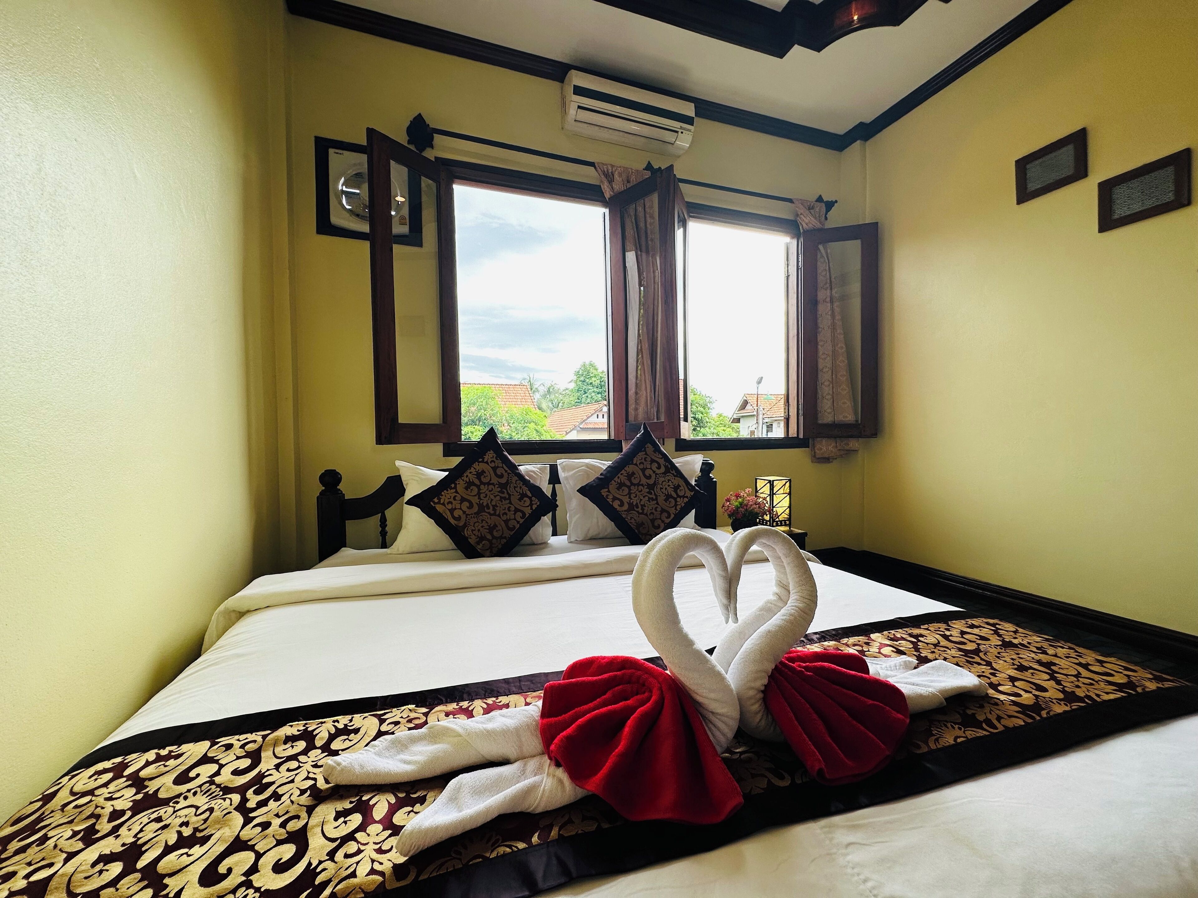 Habitación de hotel con cama, ventana con cortinas, aire acondicionado de pared y vista al exterior.