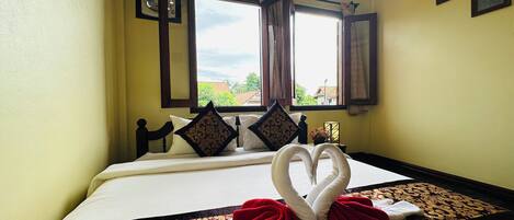 Habitación de hotel con cama, ventana con cortinas, aire acondicionado de pared y vista al exterior.