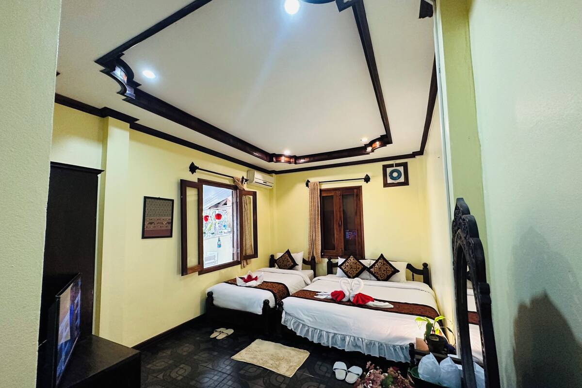 A hotel room with two beds, a television, a window with a curtain, and a ceiling with recessed lighting.