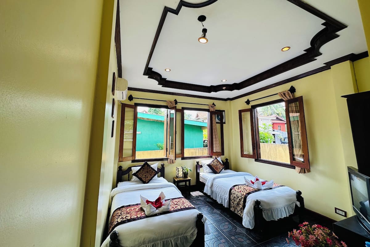 A hotel room with two beds, a television, and a ceiling fan.