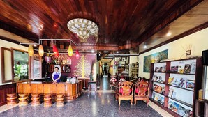 Een receptiegedeelte met een houten balie, een receptionist en een presentatie van ansichtkaarten.