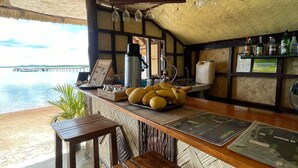 A beachside bar with a thatched roof, wooden furniture, and a view of the sea. - Concepcion Divers Lodge (Busuanga)