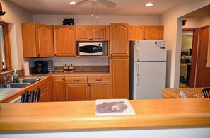 A kitchen with wooden cabinets, a microwave, a refrigerator, and a countertop with a coffee maker.