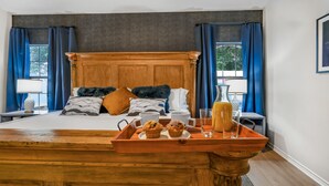 A hotel room with a large bed, a wooden headboard, and a breakfast tray with muffins and juice.