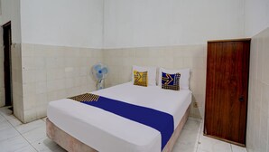 Ein Schlafzimmer mit einem Bett, einer Holztür und einem Ventilator.