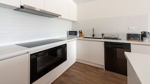 Modern kitchen with oven, dishwasher, microwave, toaster, and kettle.