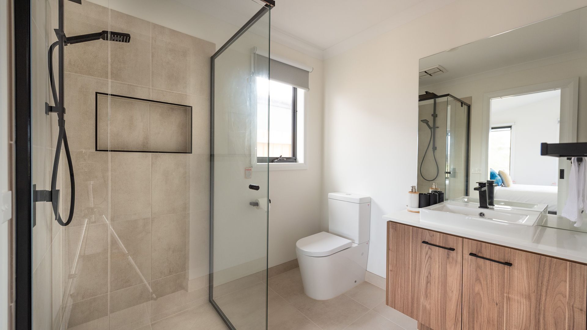 Een moderne badkamer met een douchecabine van glas, een toilet en een wastafel met spiegel.