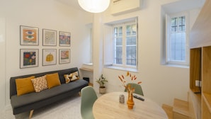 A modern living room with a grey sofa, a round table, and a hanging light fixture. - Torlonia Studio in Rome (Rome)