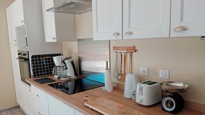Eine moderne Küche mit weißen Schränken, einer Holz Arbeitsplatte, einer Kaffeemaschine, einem Toaster und einem Wasserkocher.