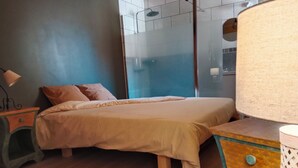 Ein Schlafzimmer mit einem Bett, Nachttischen aus Holz, einem Spiegel und einer Lampe.