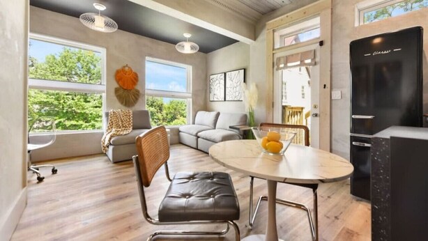 A modern living room with a dining table, leather chairs, and a black refrigerator. - ★ HostWise Stays ★ 2 Apartments in 1 - Great Privacy, Beautiful Space! (Pittsburgh)