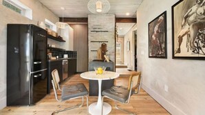 A modern kitchen with a black refrigerator, a round dining table with two chairs, and a hanging light fixture. - ★ HostWise Stays ★ 2 Apartments in 1 - Great Privacy, Beautiful Space! (Pittsburgh)