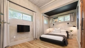 A modern bedroom with a large bed, a flat-screen TV mounted on the wall, and a window with curtains. - ★ HostWise Stays ★ 2 Apartments in 1 - Great Privacy, Beautiful Space! (Pittsburgh)