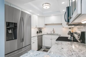 Una cocina moderna con armarios blancos, electrodomésticos de acero inoxidable y encimera de mármol.