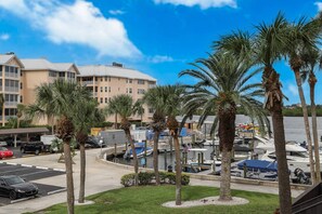 Una marina con barcos amarrados, palmeras y un hotel al fondo.