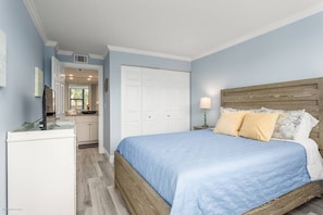 A bedroom with a bed, a nightstand, a lamp, and a wardrobe.