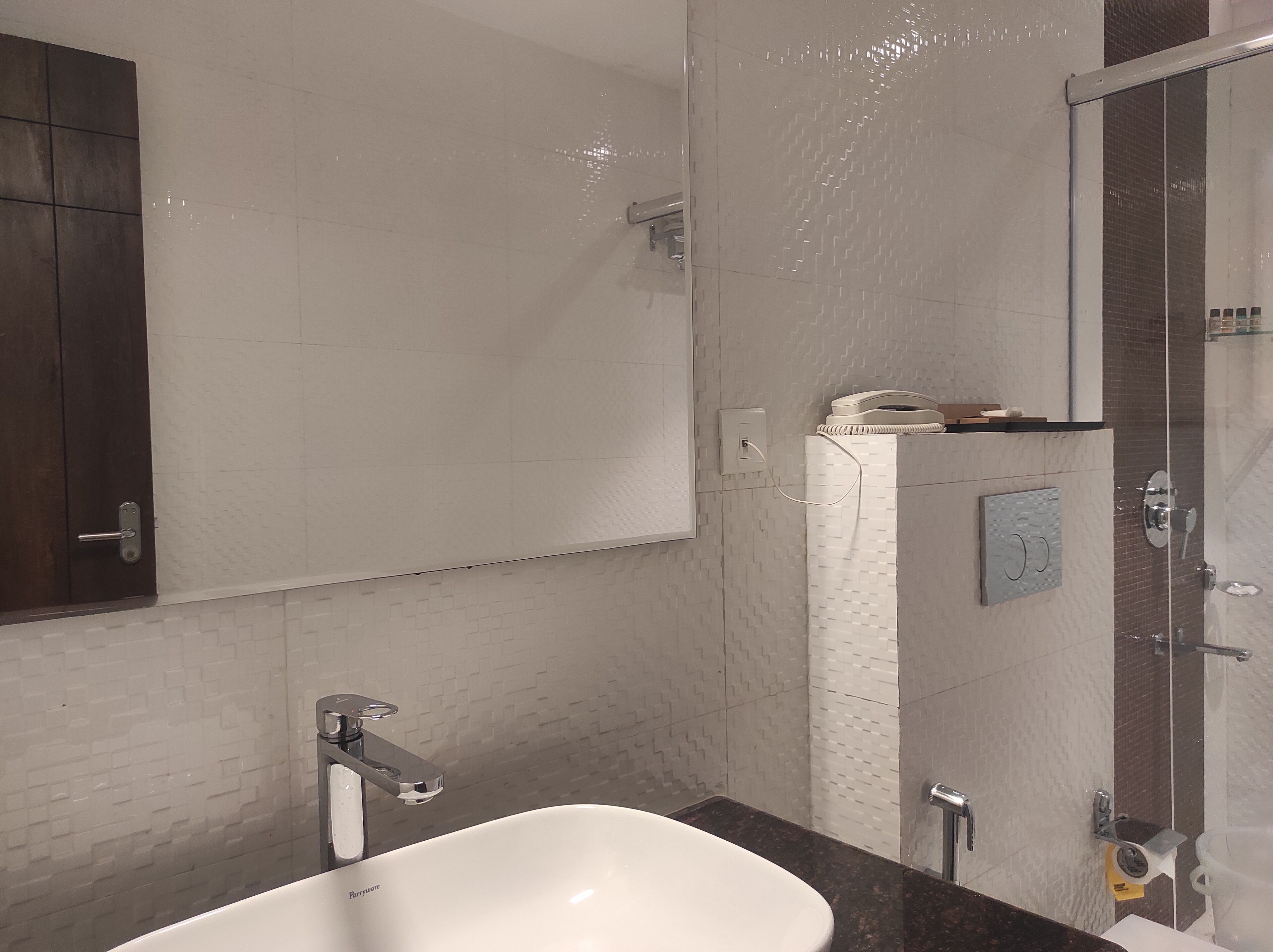 Un baño con lavamanos blanco, un espejo, ducha y retrete.