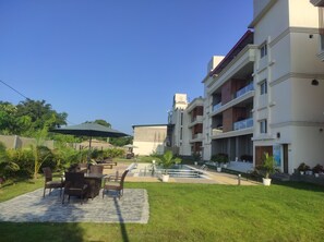 A courtyard with outdoor seating, a swimming pool, and a multi-story building with balconies.