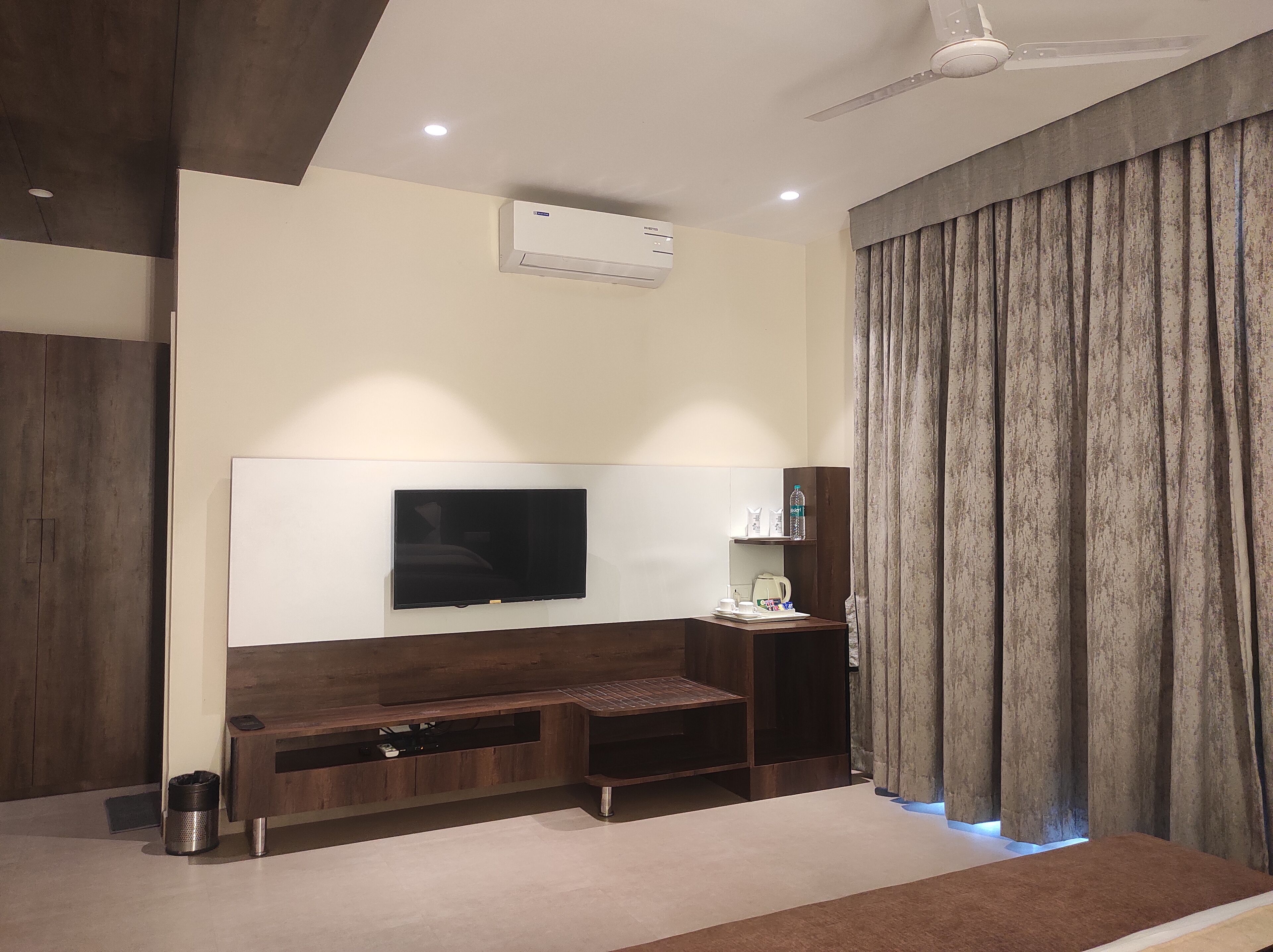 Una sala de estar moderna con un televisor de pantalla plana montado en una pared de madera, un ventilador de techo y un banco empotrado con almacenamiento.