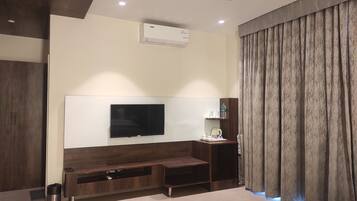 Una sala de estar moderna con un televisor de pantalla plana montado en una pared de madera, un ventilador de techo y un banco empotrado con almacenamiento.