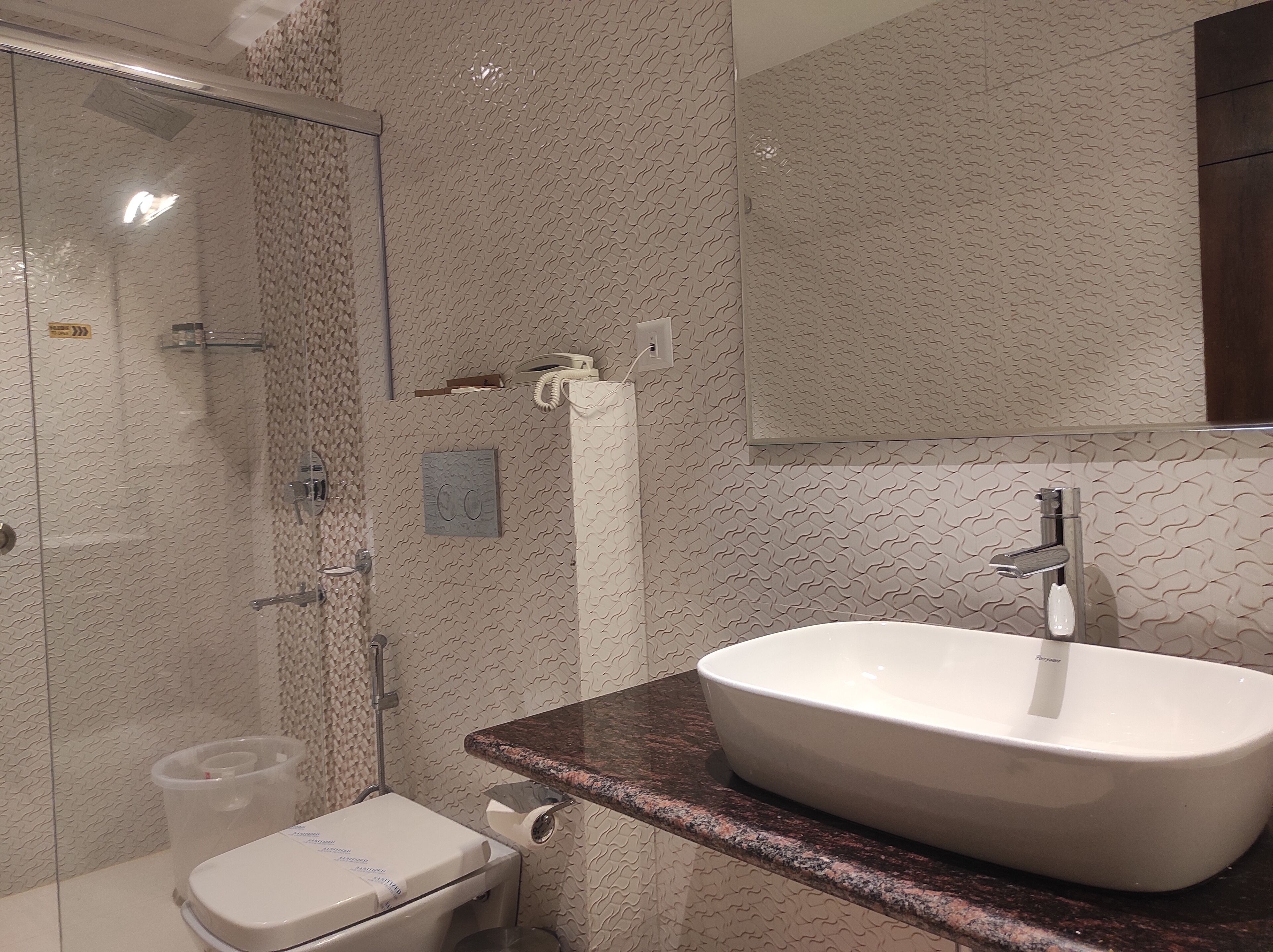 Un baño moderno con cabina de ducha de vidrio, un lavabo blanco con encimera de mármol y un inodoro.