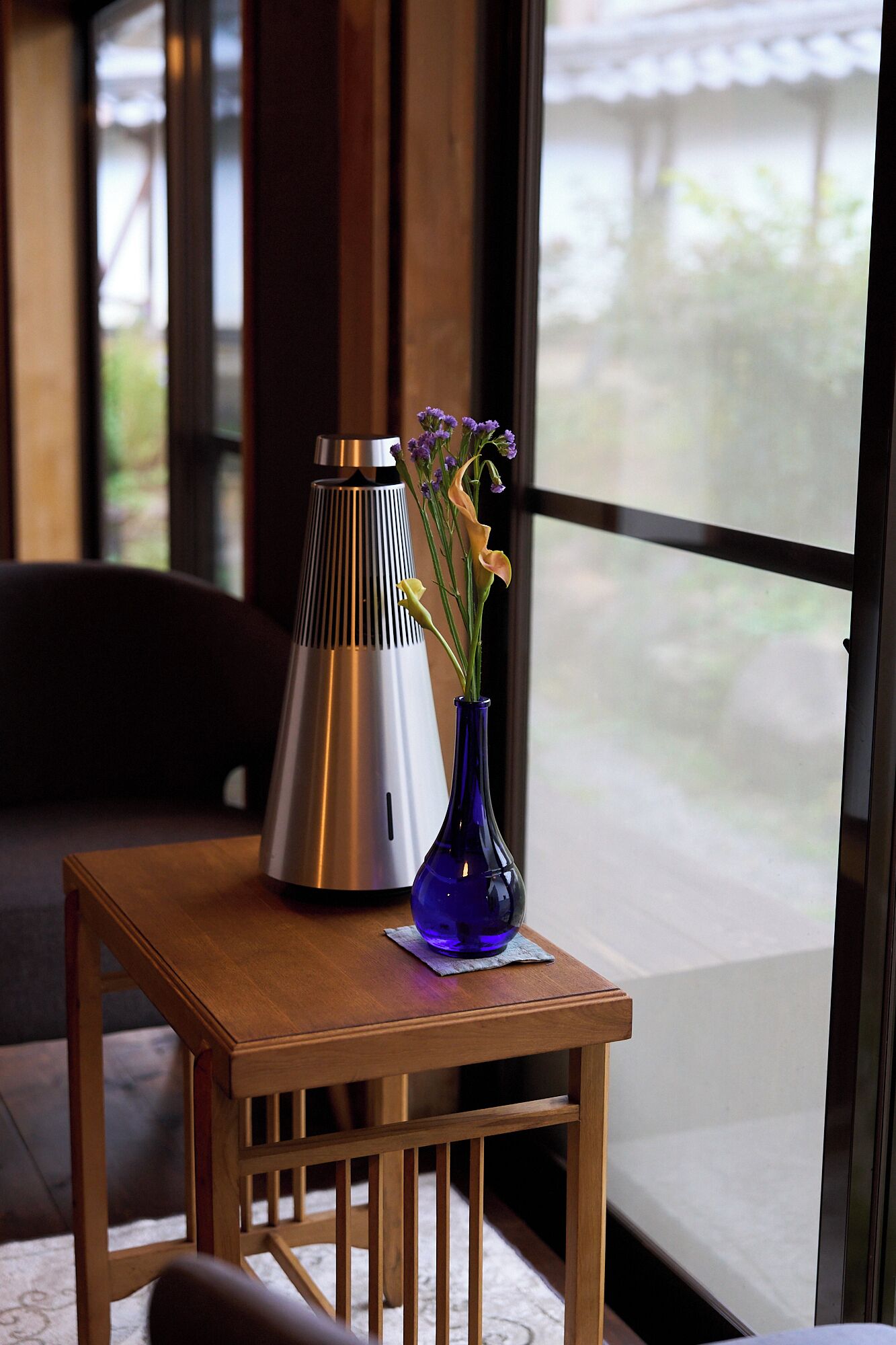 A wooden table with a blue vase and a metallic lamp.