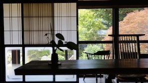 A room with a large window, a wooden table, and a chair. - Ryokan Tsuchi to Ito (Omi)