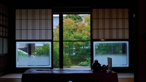 A traditional Japanese room with tatami flooring, a low table, and sliding doors with a view of autumn foliage. - Ryokan Tsuchi to Ito (Omi)