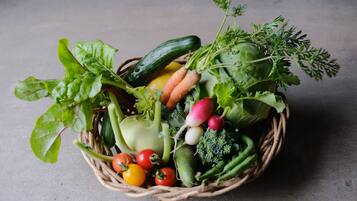 Una cesta repleta de verduras frescas como lechuga, zanahorias, tomates y pepinos.