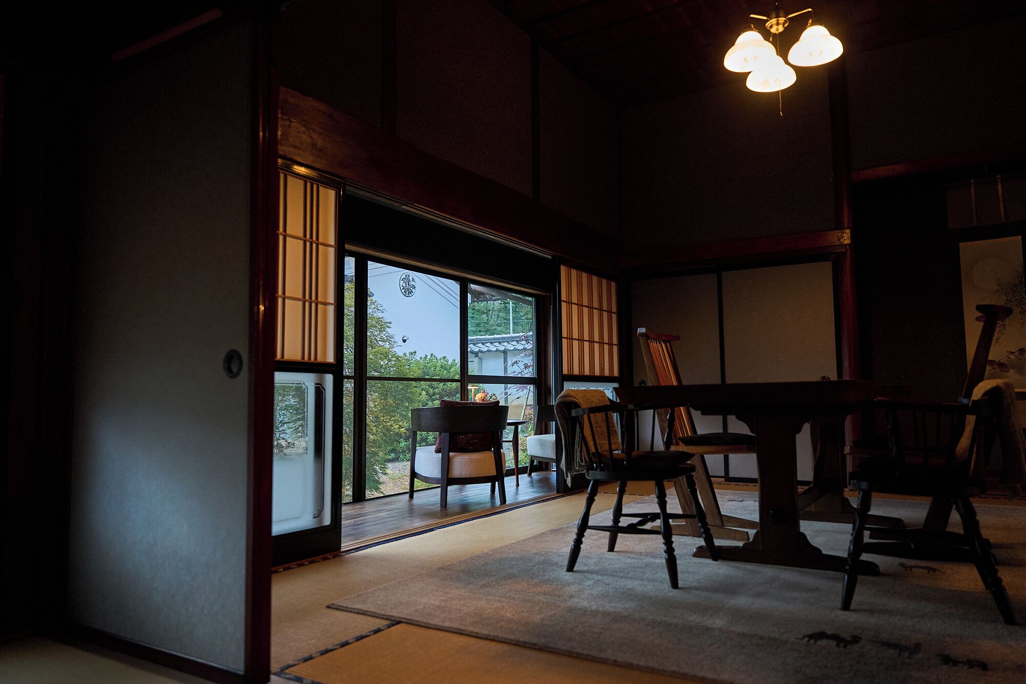 Une pièce de style japonais traditionnel, avec un sol recouvert de tatamis, des portes coulissantes et une vue sur un jardin.