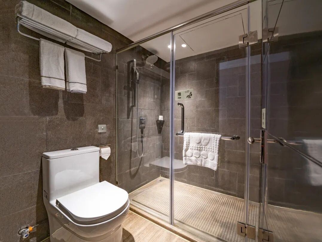 A modern bathroom with a glass-enclosed shower, a toilet, and a towel rack.