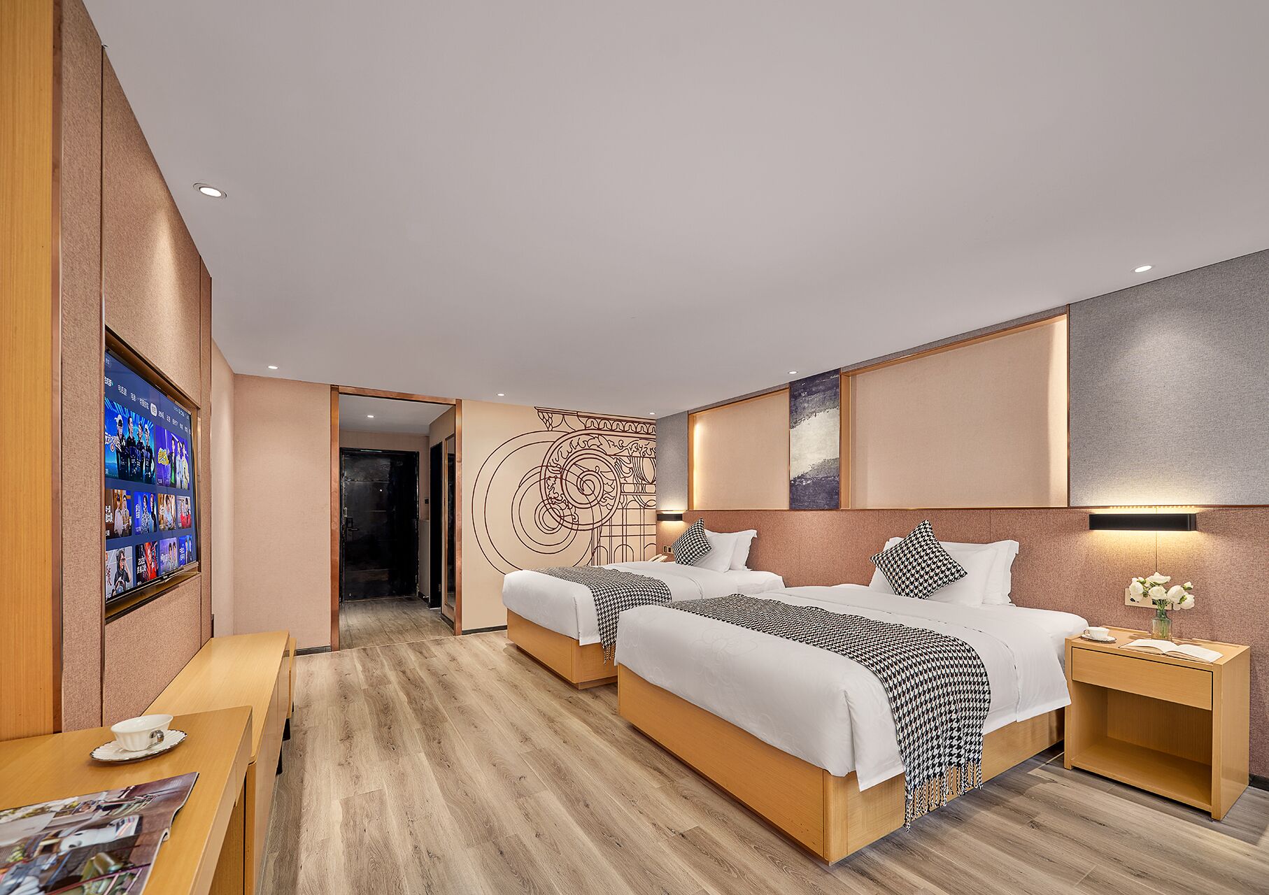 A modern hotel room with a large bed, bedside tables, a TV, and a decorative wall.