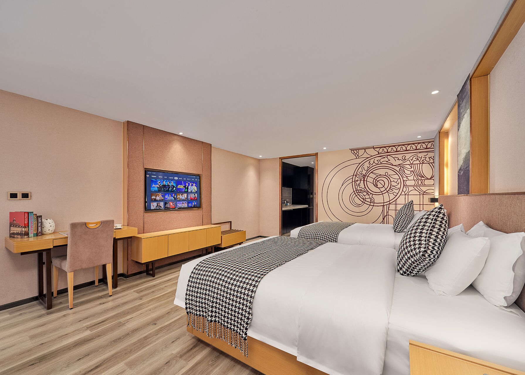Moderni hotellihuone, jossa on suuri sänky, työpöytä tietokoneella ja seinälle asennettu televisio.