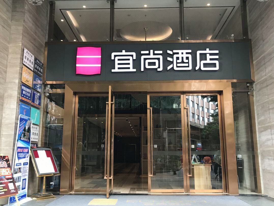 The entrance to a hotel with a prominent sign, glass doors, and a visible interior through the entrance.