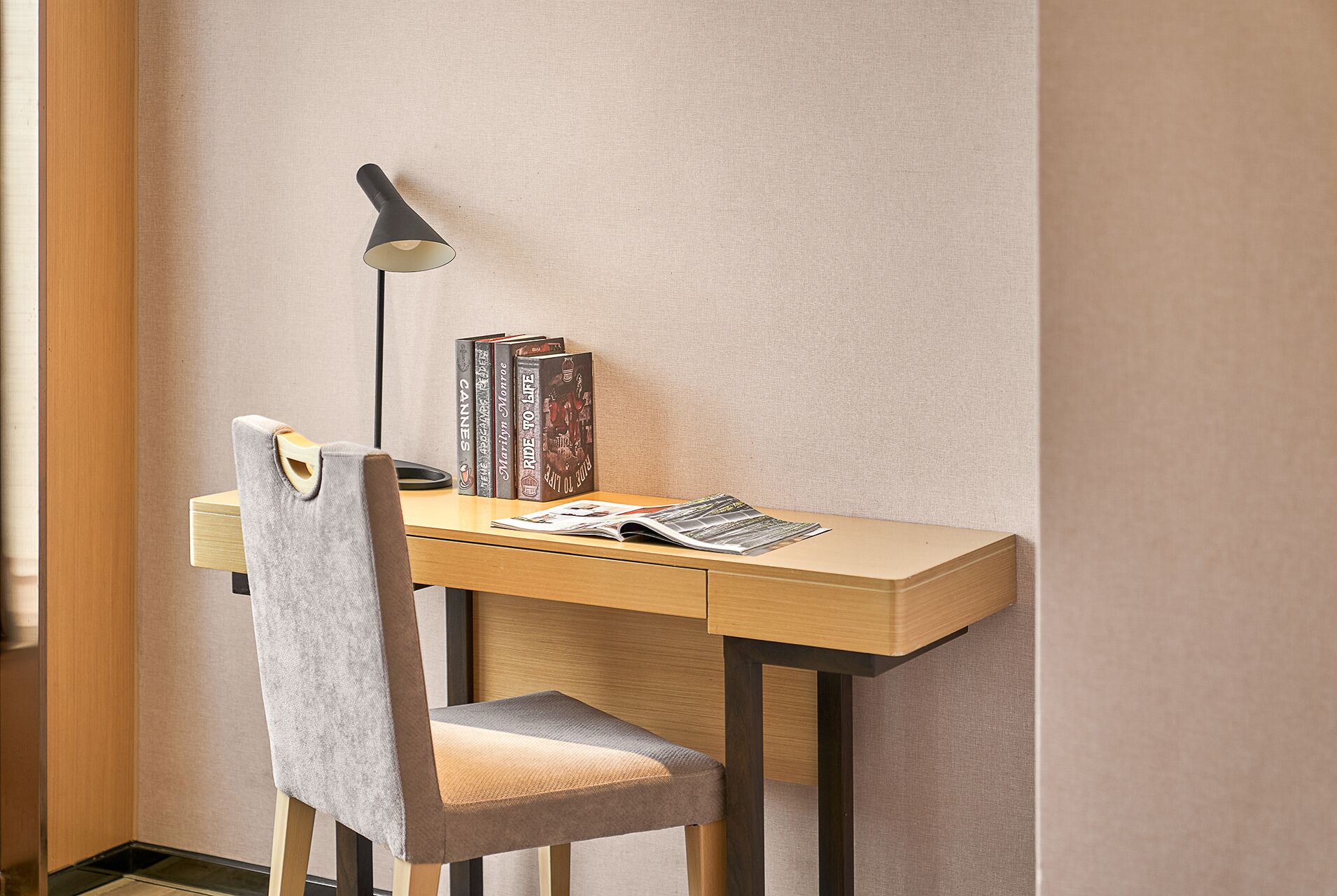A compact desk with a chair, a lamp, and books.