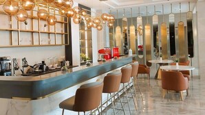 Un área de bar moderna con mostrador de mármol, taburetes y una lámpara esférica original.