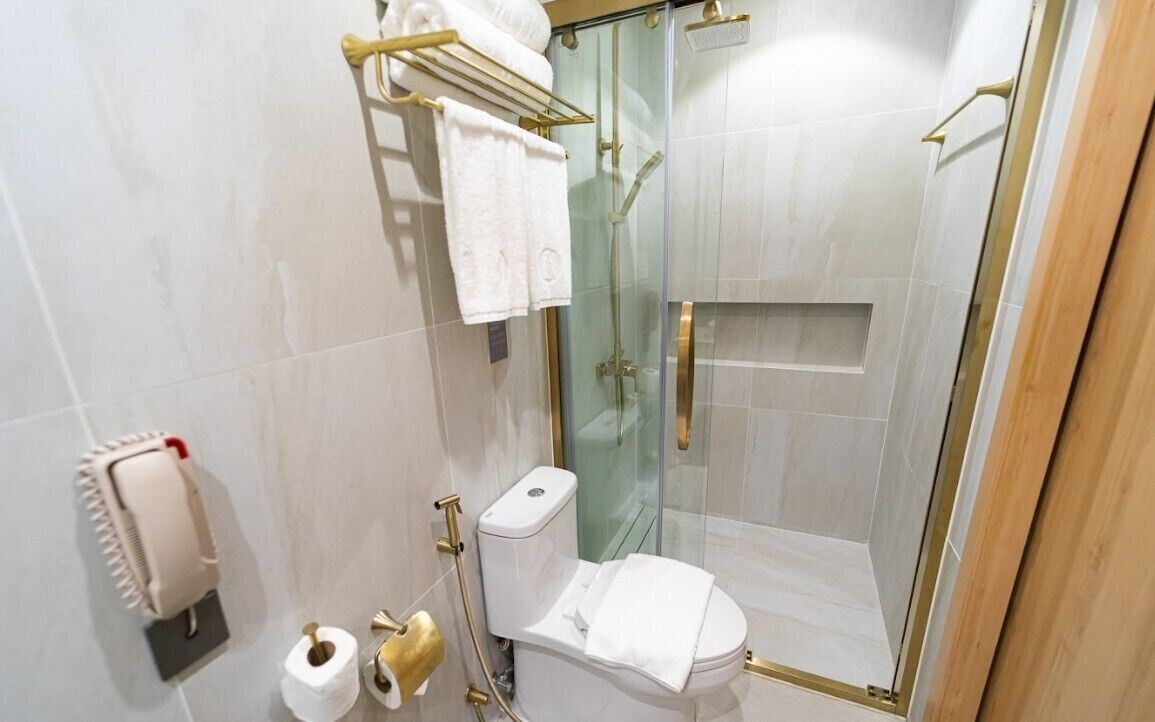 Un baño moderno con ducha de vidrio, inodoro y toallero.