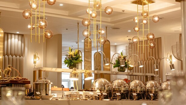 Un comedor bien iluminado con múltiples candelabros, una mesa de buffet y un espejo que refleja el salón.