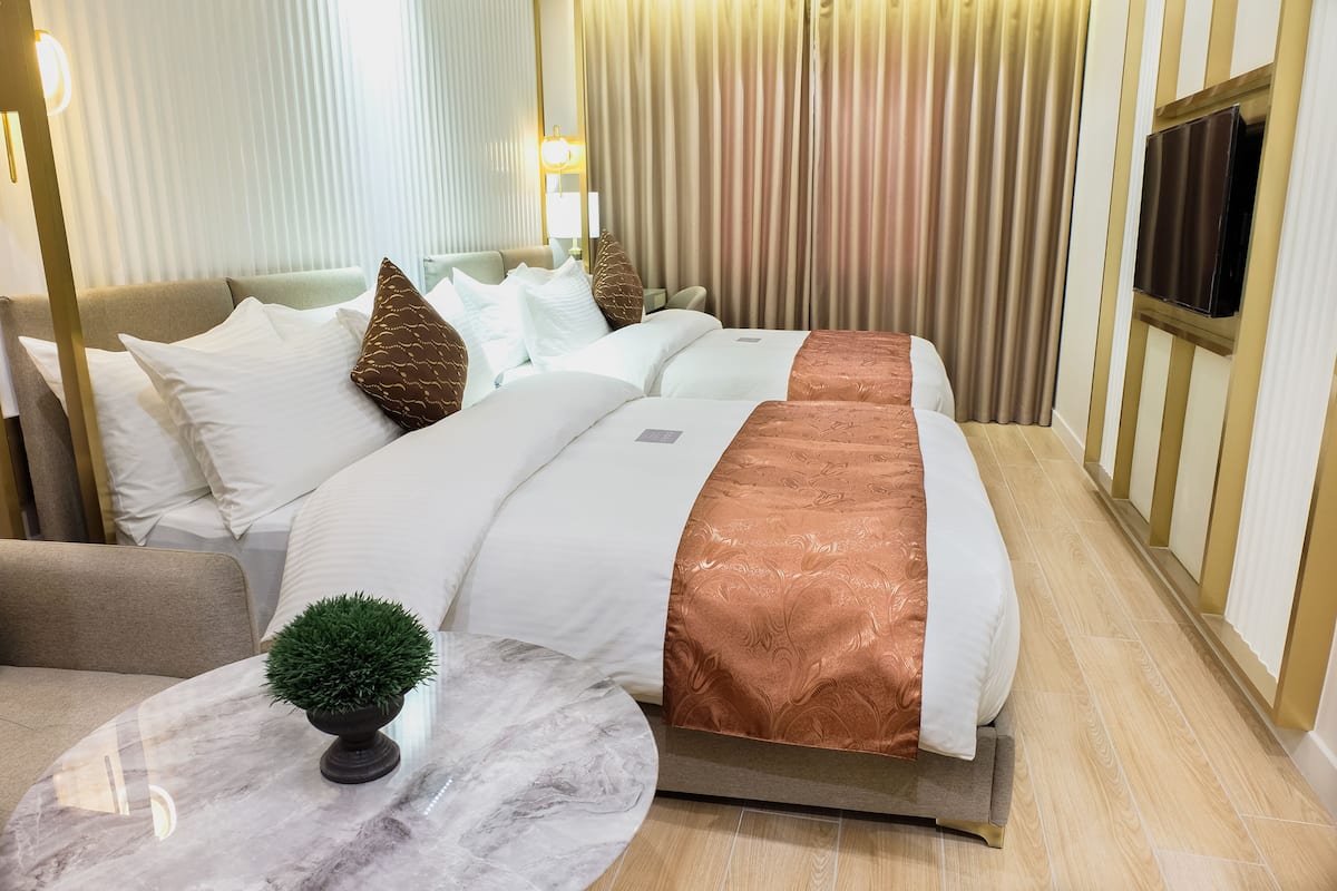A hotel room with a large bed, a small round table with a plant, and a TV mounted on the wall.