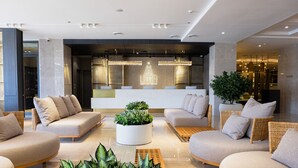Un vestíbulo moderno con sofás, un mostrador de recepción y una planta grande.