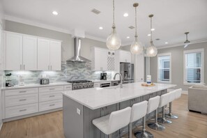 A modern kitchen with white cabinetry, a central island with bar stools, stainless steel appliances, and pendant lighting. - 5BR Luxury 3-Story Home w/ Private Pool! ~ Sealestial at Seacrest Beach, 30A (Inlet Beach)