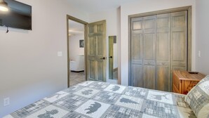 Ein Schlafzimmer mit einem Bett, einem Holzschrank, einem Fernseher und einem kleinen Holztisch.