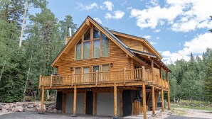 Une cabane en bois dotée d’un balcon, de grandes fenêtres et d’un garage.