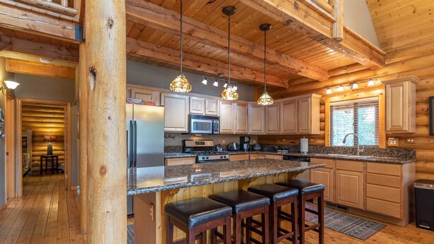 Une cuisine spacieuse dotée de meubles en bois, de plans de travail en granit et d’un îlot central avec des tabourets de bar.