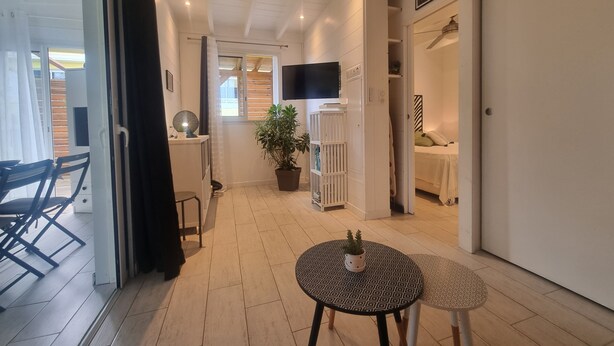 Una sala de estar moderna con una mesa redonda, una planta en maceta y un televisor montado en la pared.